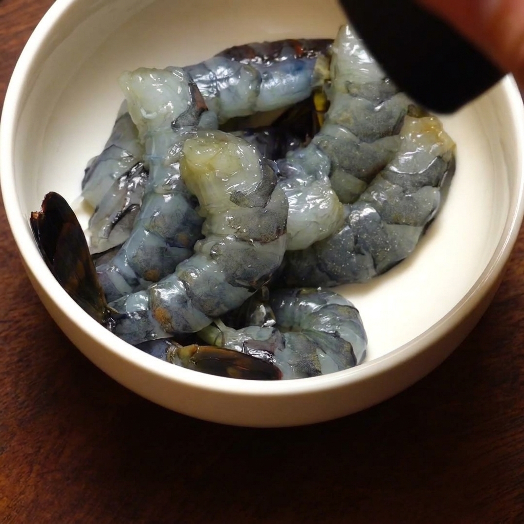 Un bol de gambas décortiquées assaisonnées de poivre noir fraîchement moulu à partir dun moulin.