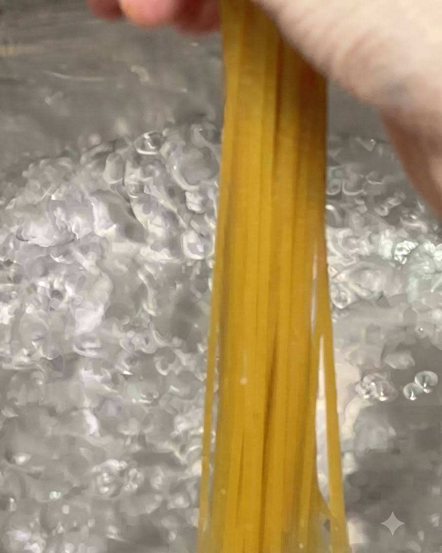 Des spaghettis plongés dans une grande marmite deau bouillante à gros bouillons.