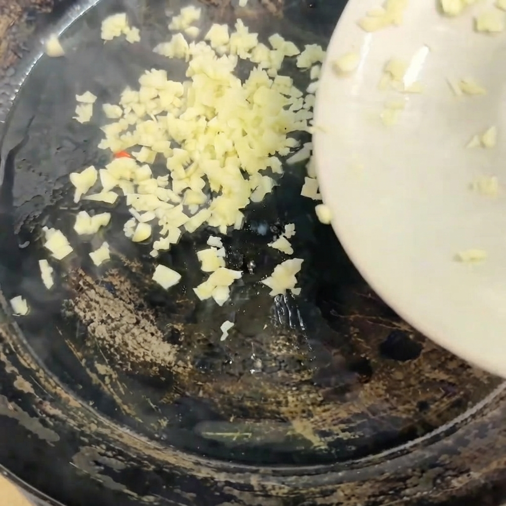 De lail haché versé dune assiette blanche dans une poêle chaude.