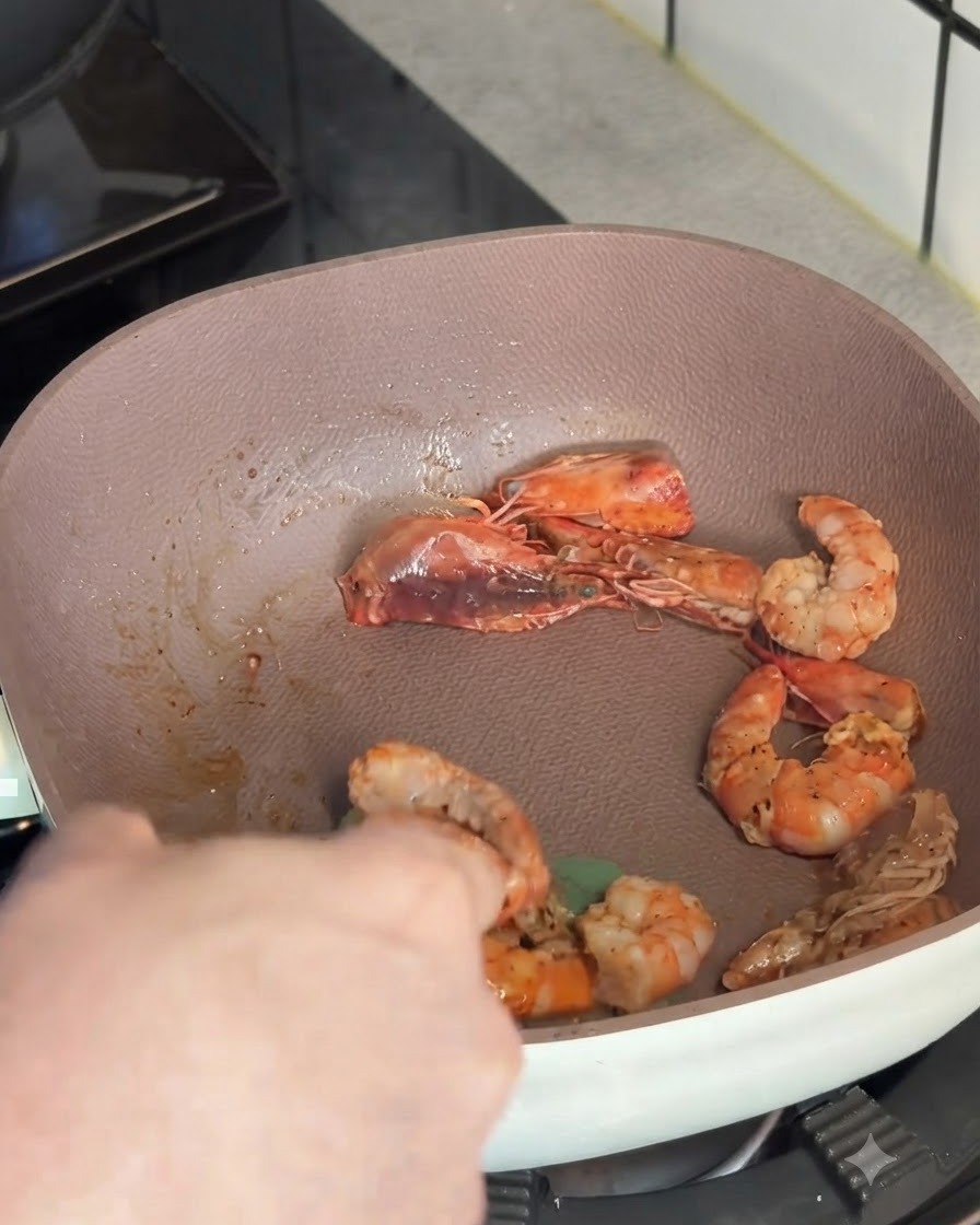 Crevettes roses sautées retirées dune poêle peu profonde à laide dun ustensile de cuisine.