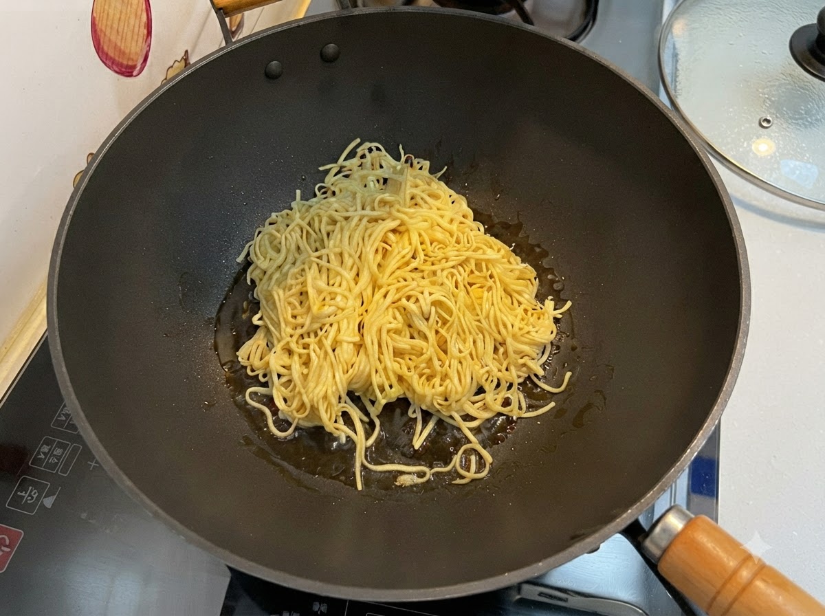 Nouilles E-fu égouttées en train dêtre sautées dans un wok noir à laide dune spatule.
