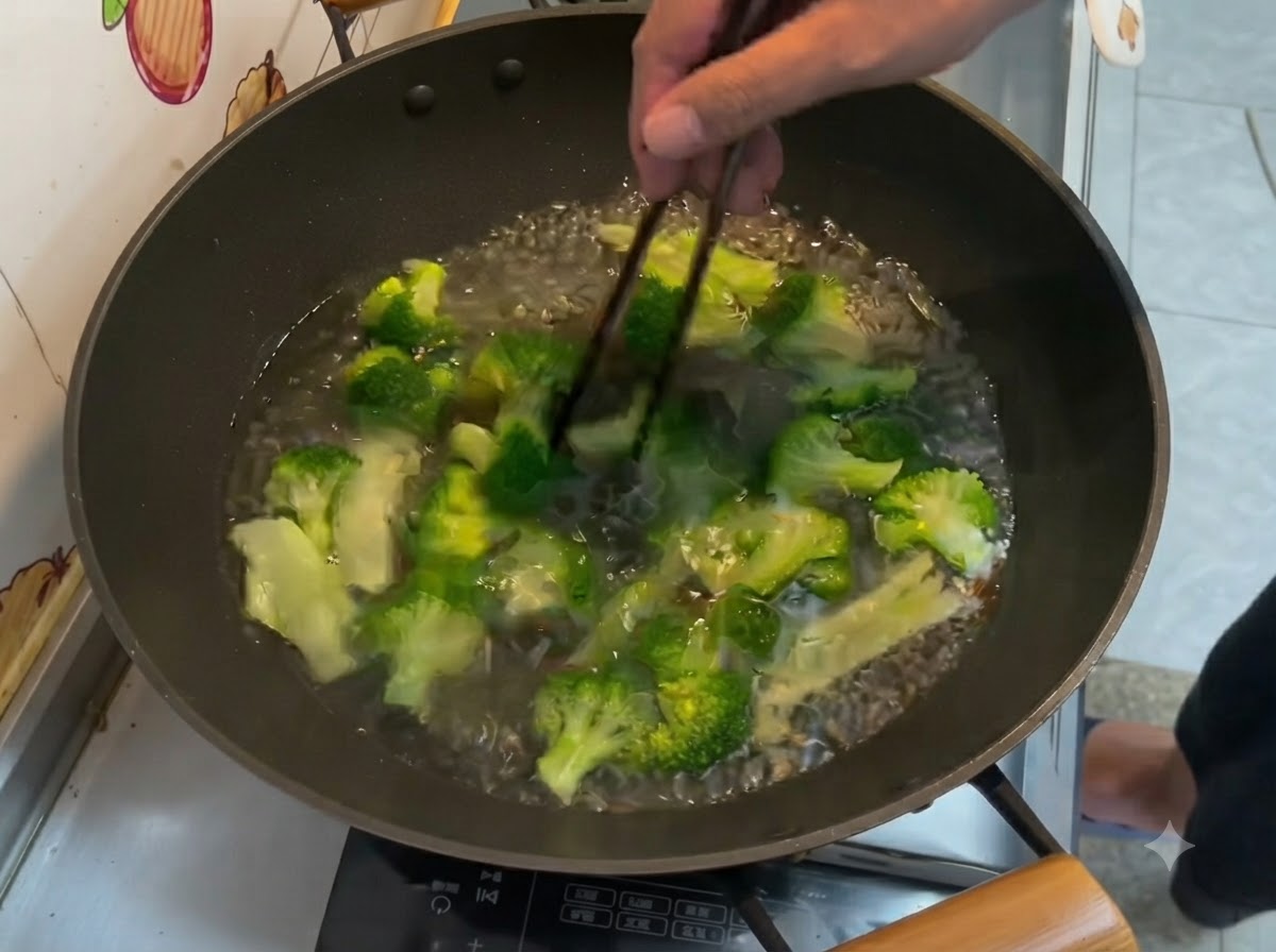 Fleurettes de brocoli vert vif bouillant dans de leau à lintérieur dun wok, remuées avec des baguettes.