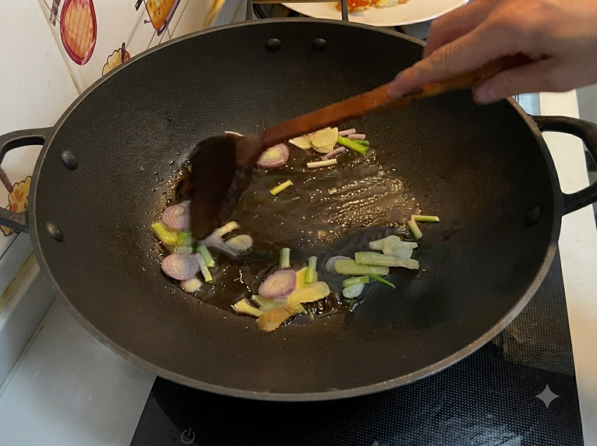 Gingembre tranché, ail, échalote et oignons verts frits dans de lhuile chaude à lintérieur dun wok, remués avec une spatule en bois.