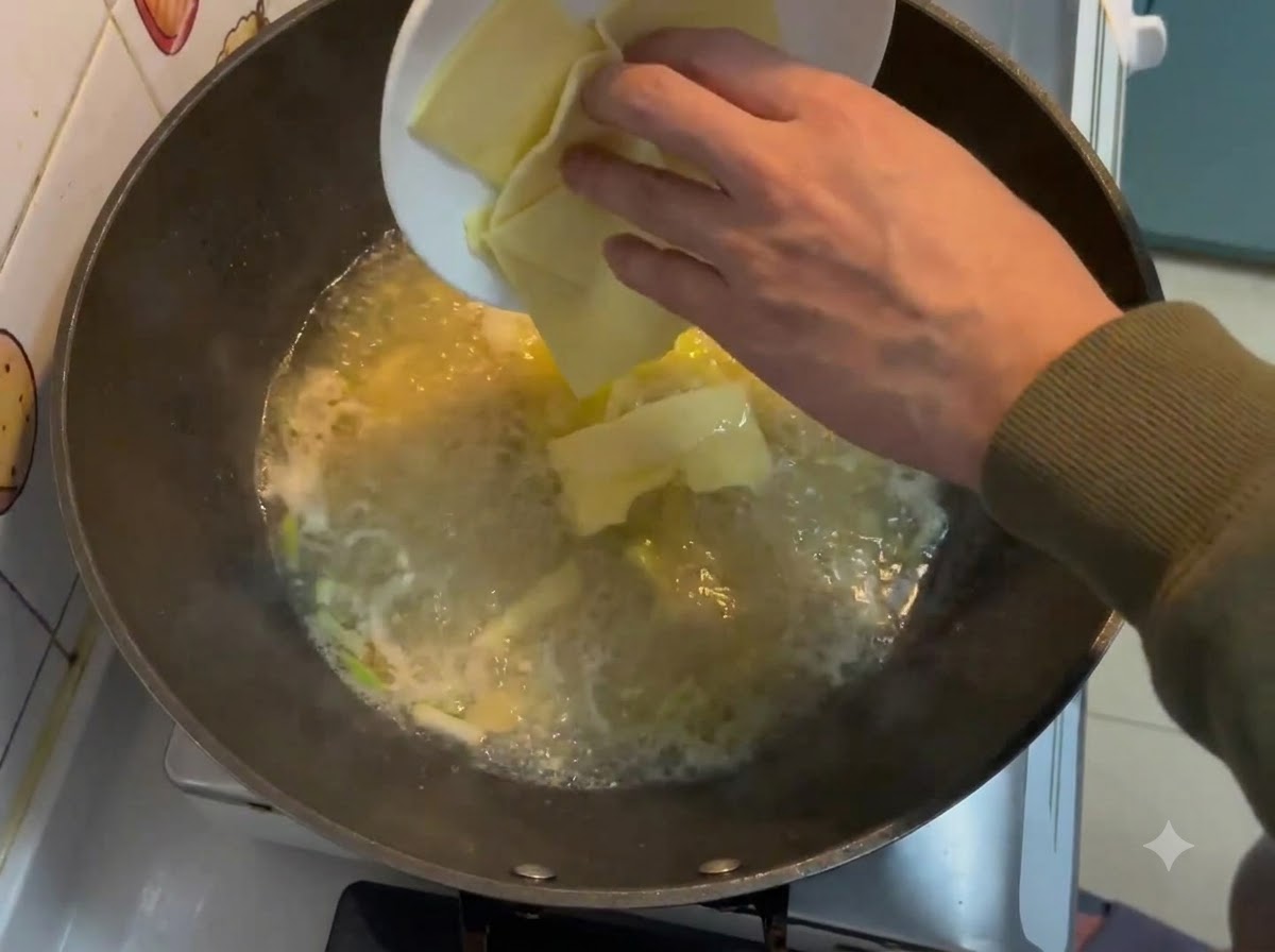 Tranches de fromage carrées tombant dune assiette blanche dans un bouillon crémeux bouillant dans un wok.