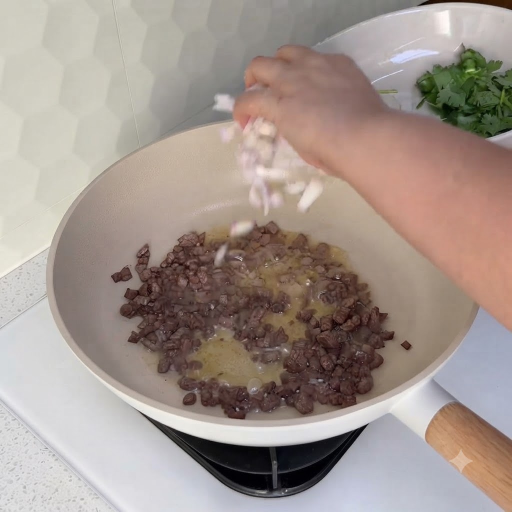 Oignons en dés saupoudrés dans un wok contenant le bœuf haché cuit.