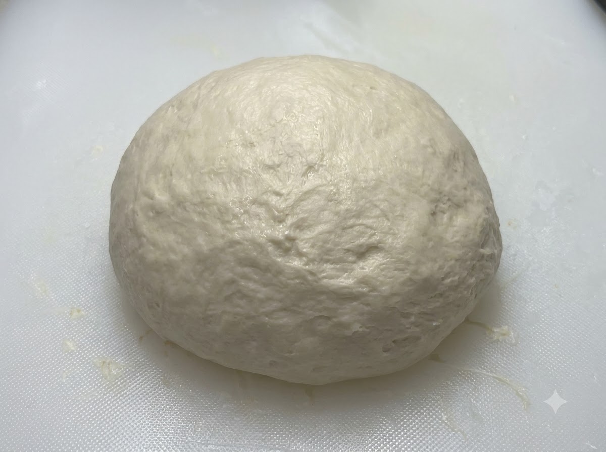 Une boule de pâte lisse reposant sur une planche blanche avant dêtre recouverte.