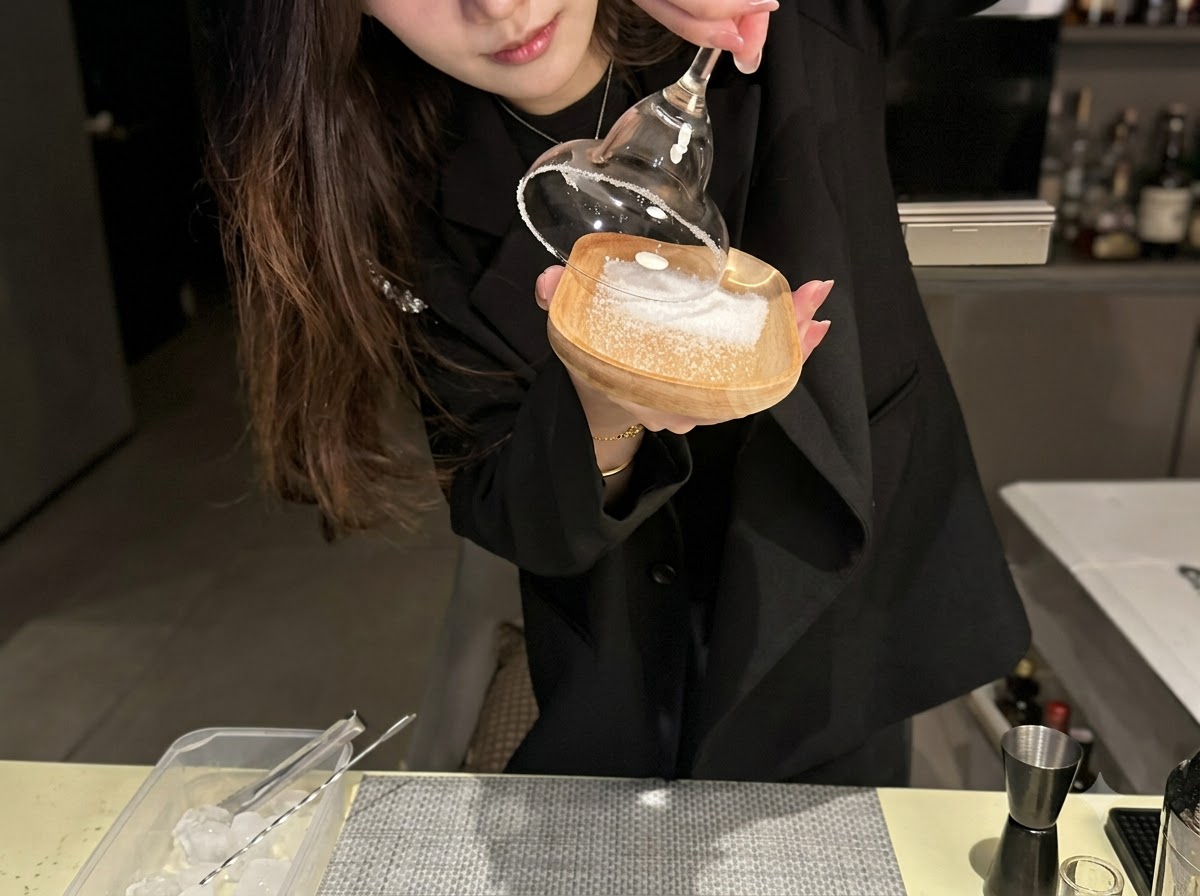 Le bord dun verre à cocktail pressé dans une couche de sel de mer sur une petite assiette en bois.
