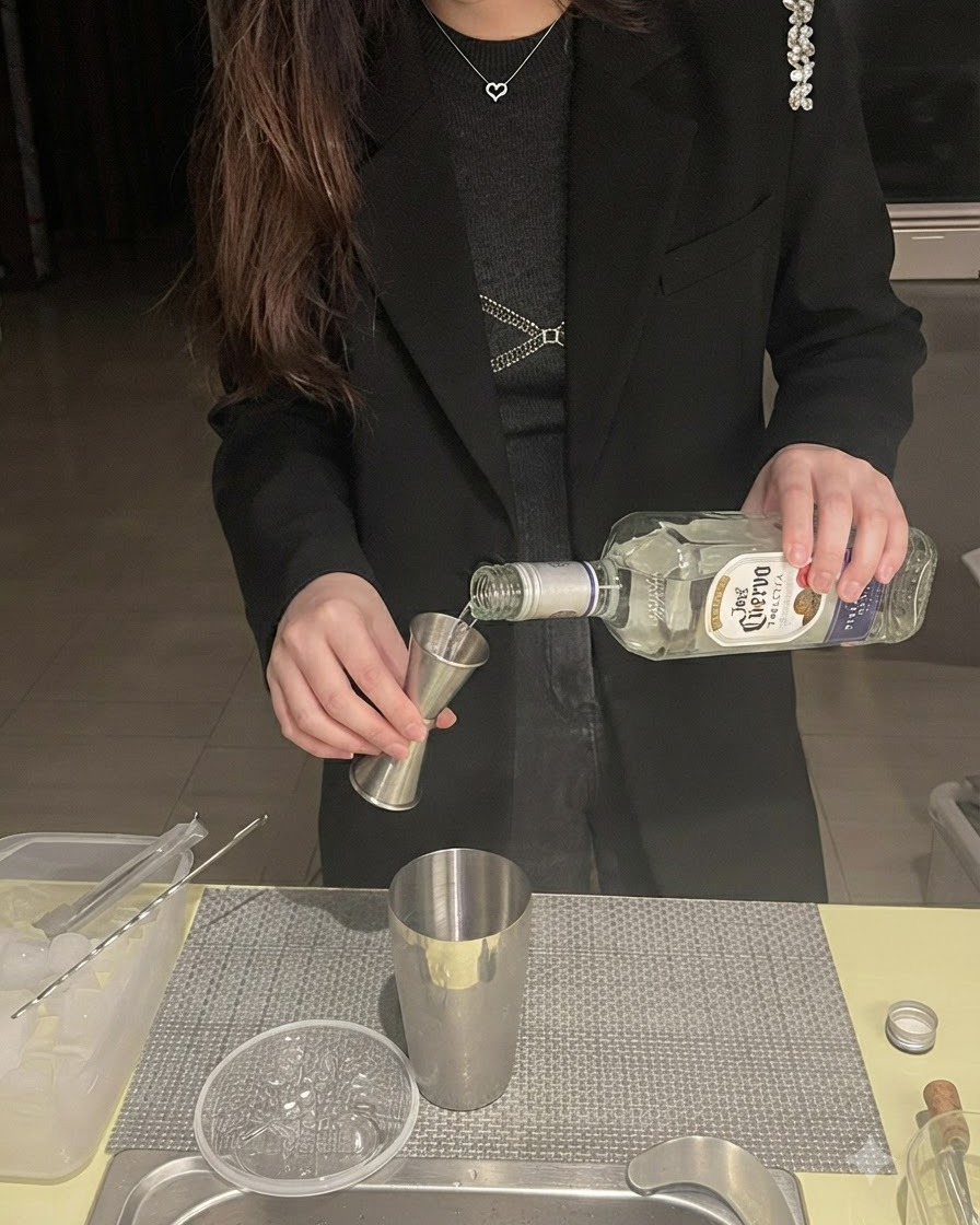De la tequila versée dune bouteille dans un doseur placé au-dessus dun shaker en métal.