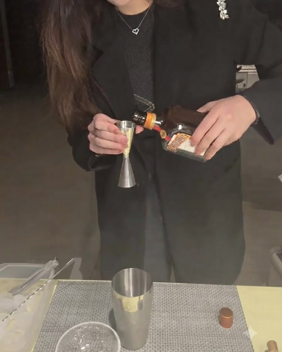 Du Cointreau versé dans un doseur au-dessus dun shaker.