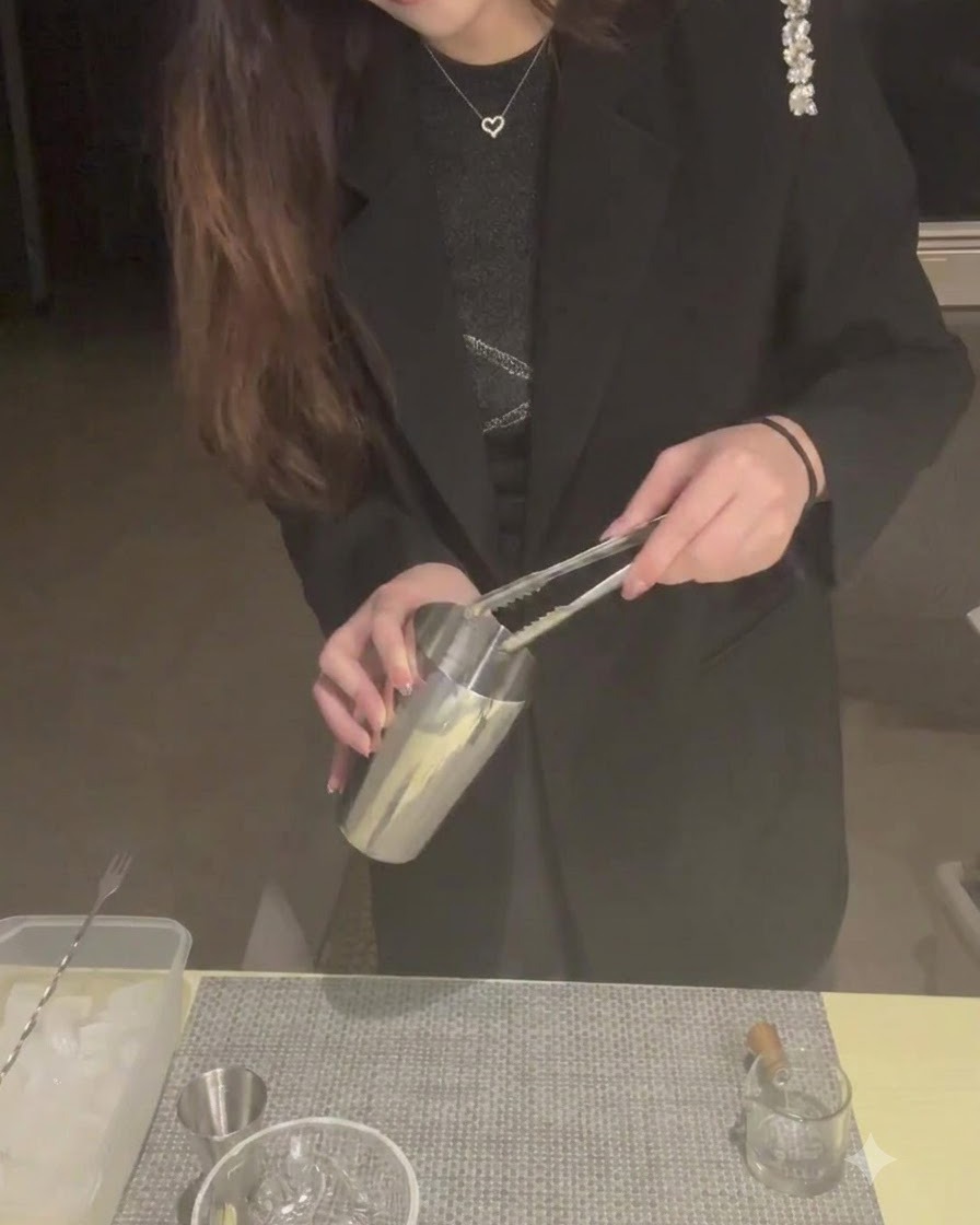 Une personne utilisant des pinces pour placer des glaçons dans un shaker en métal.