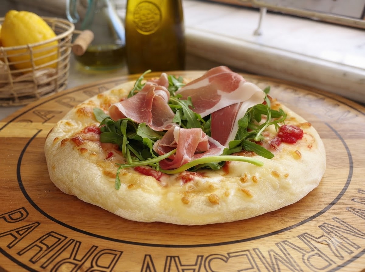 Du fromage parmesan fraîchement râpé tombant sur une pizza préparée garnie de légumes verts et de viande séchée.