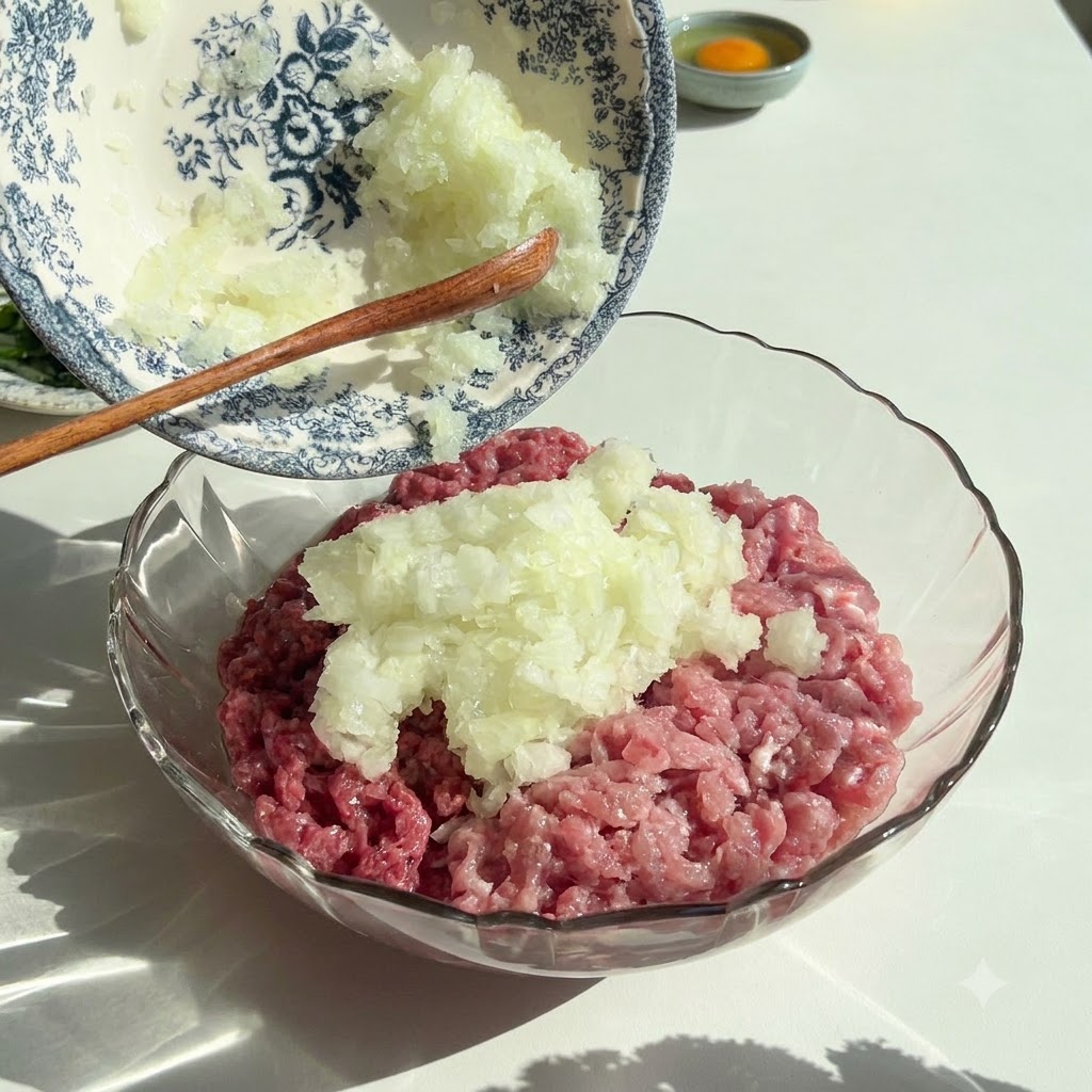 Des oignons et du persil finement hachés versés dun bol décoratif dans un bol en verre contenant de la viande hachée crue.