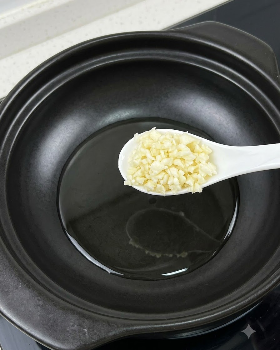 Une cuillerée dail émincé tenue au-dessus dune casserole à côté dun jaune dœuf séparé.