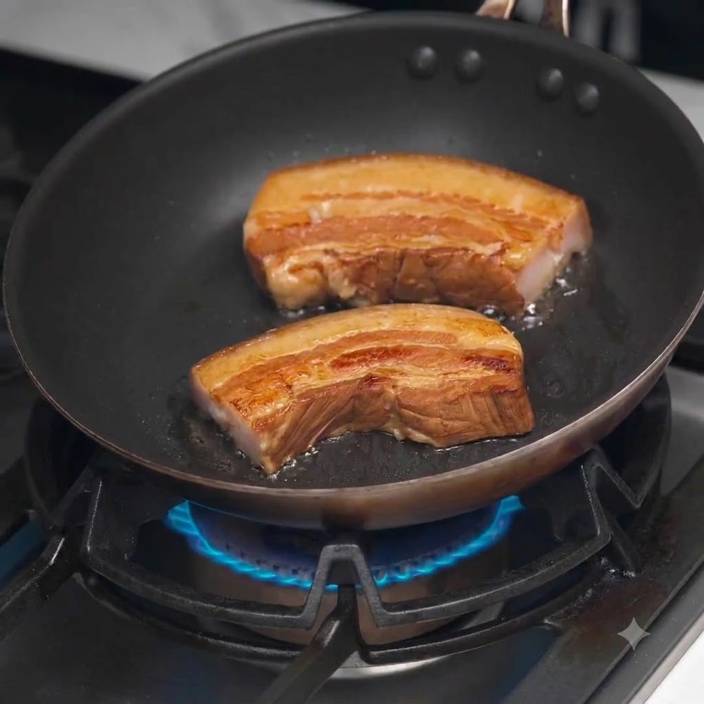 Tranches épaisses de poitrine de porc braisée dorant et croustillant dans une poêle noire chaude sur une cuisinière à gaz.