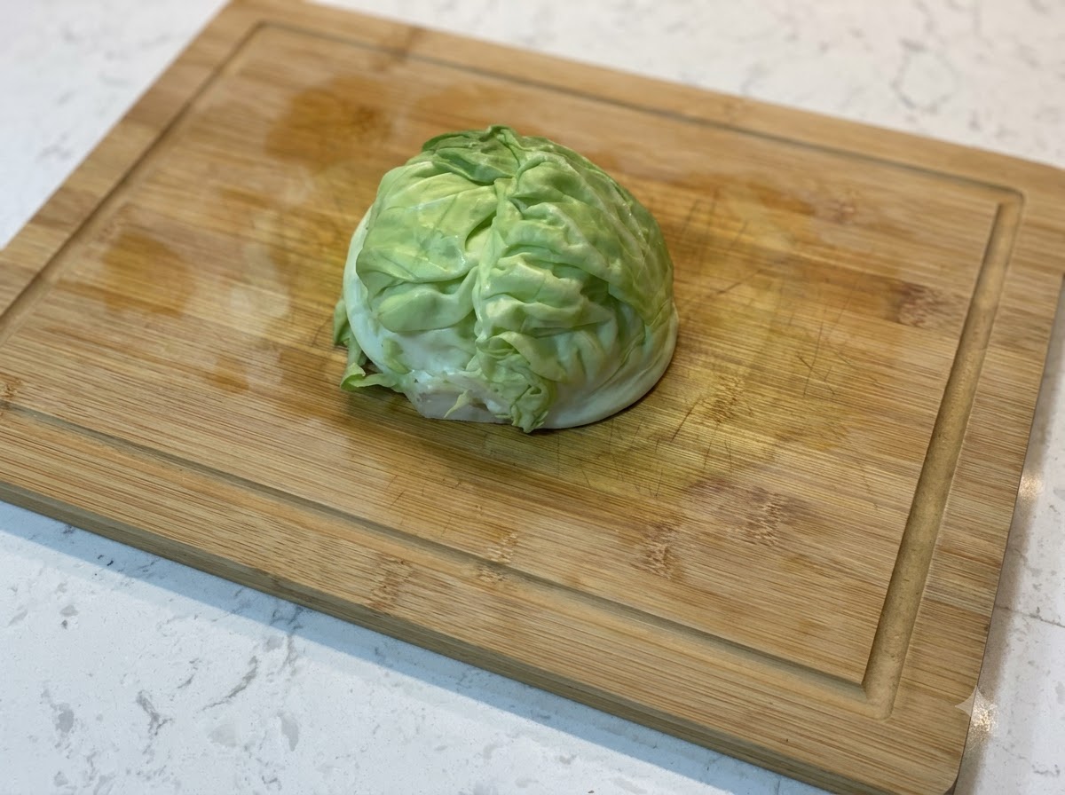 Un quartier de chou vert frais reposant sur une planche à découper en bois.