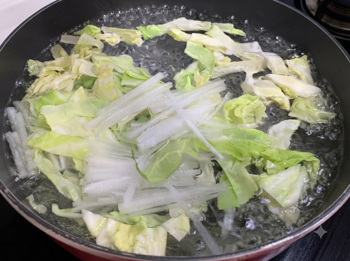Chou émincé et radis blanc en train de bouillir dans une casserole deau.