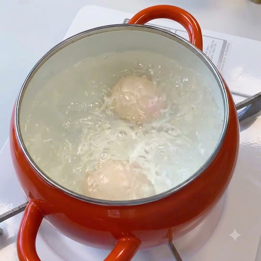 Des œufs bouillant vigoureusement à lintérieur dune casserole deau orange.