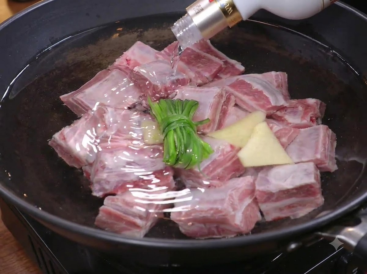 Morceaux de bœuf plongés dans une marmite deau avec de la ciboule et du gingembre pour les blanchir.