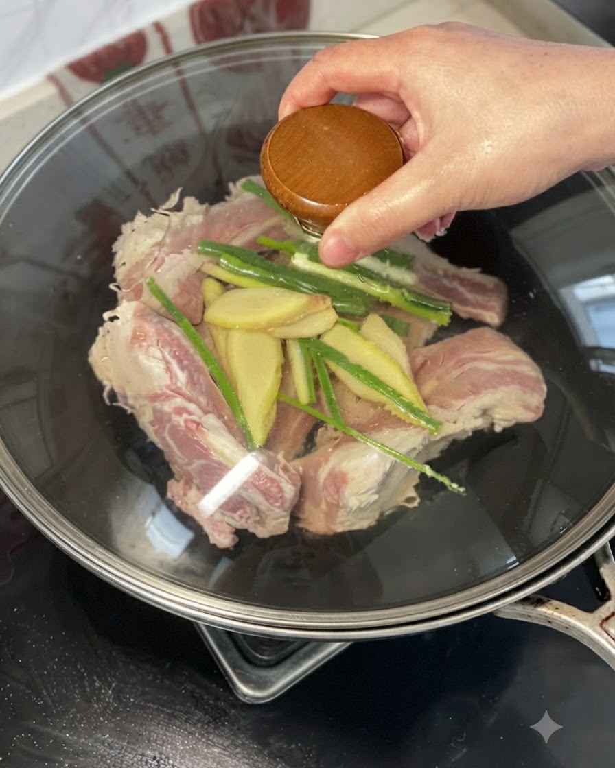 Une main tenant un couvercle ou versant du vin jaune sur les côtes de bœuf, le gingembre et la ciboule dans un wok.