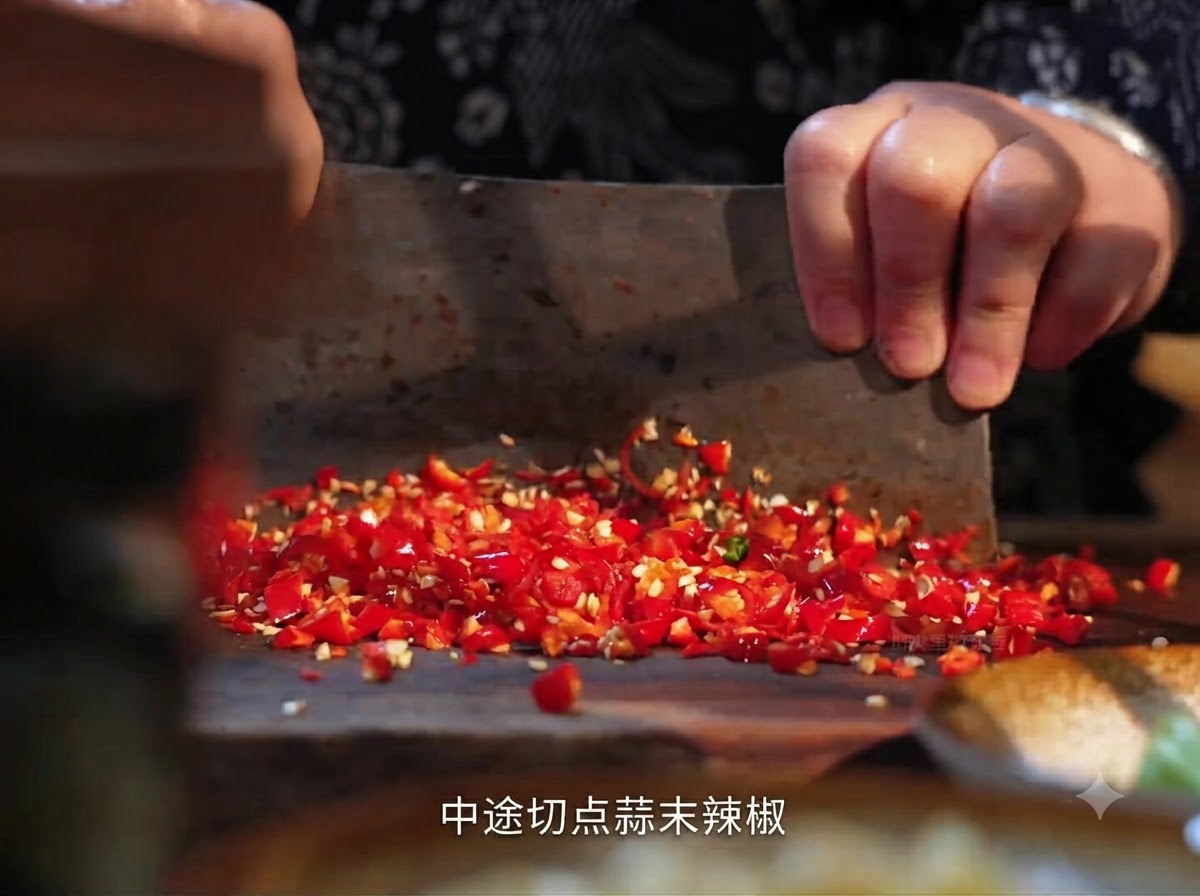 Piments rouges frais en train dêtre coupés sur une planche en bois avec un hachoir.