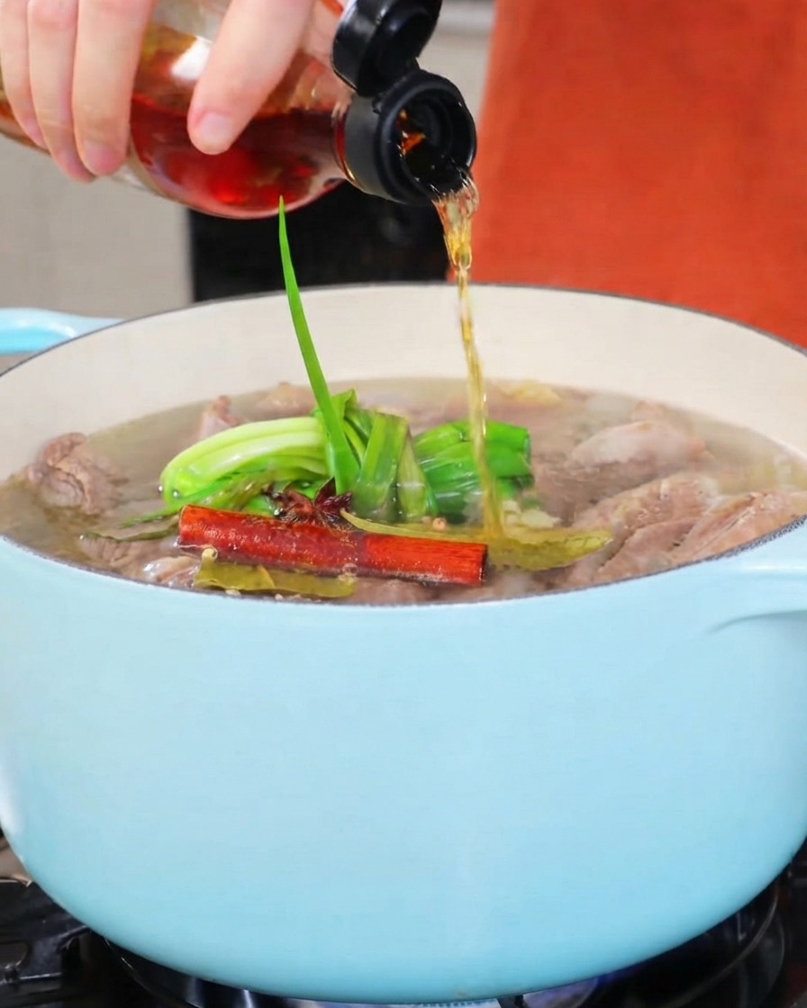 Vin de cuisine versé dune petite bouteille dans une casserole de ragoût de couleur claire.