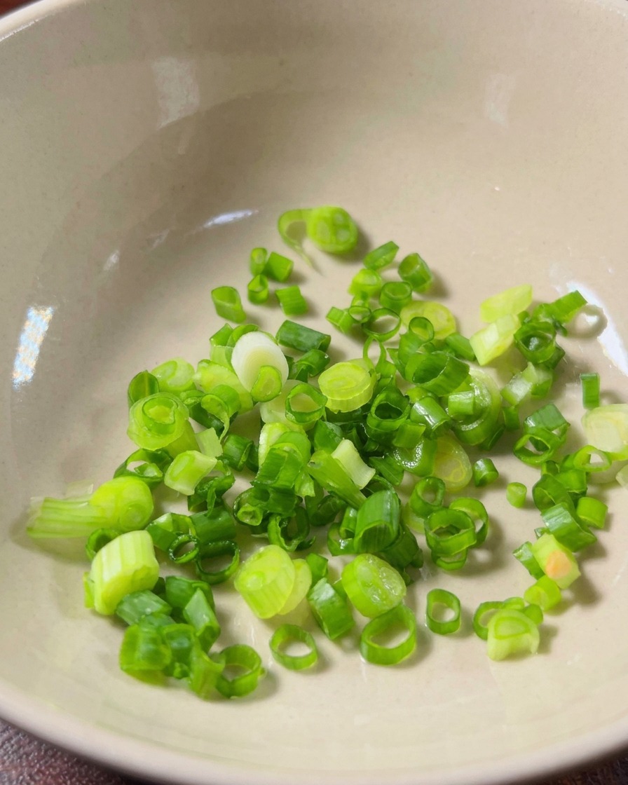 Ail finement émincé et tranches de piment millet rouge frais placés à lintérieur dun bol en céramique propre.
