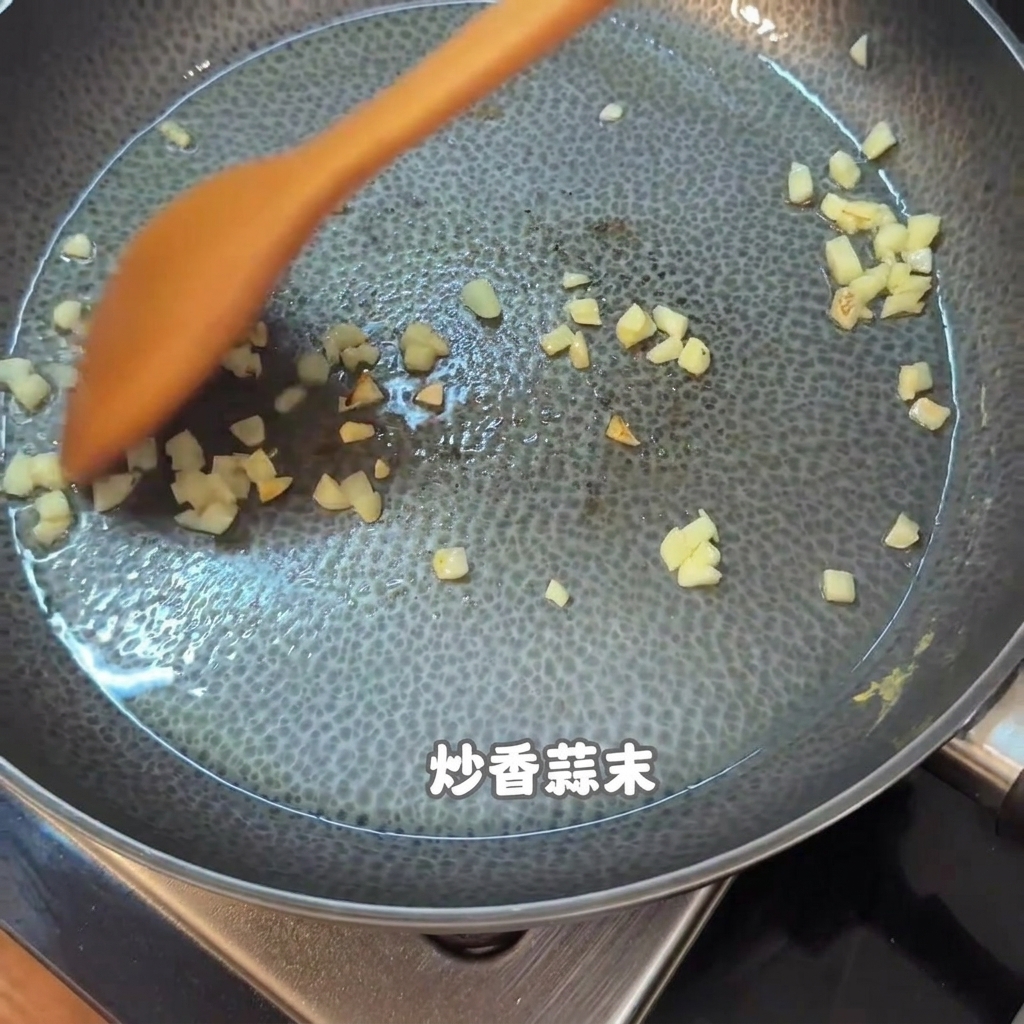 De lail haché et des morceaux de nourriture remués avec une spatule en bois orange dans une poêle antiadhésive.