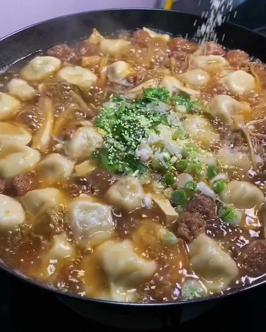 Poudre de bouillon de poulet saupoudrée par-dessus le wok bouillonnant.
