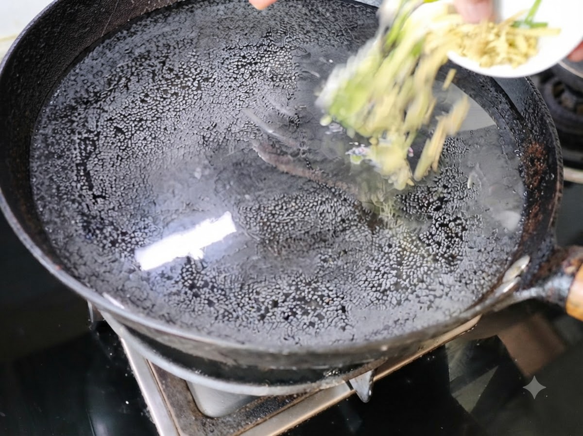 Des échalotes et du gingembre hachés ajoutés dans un wok deau sur la cuisinière.