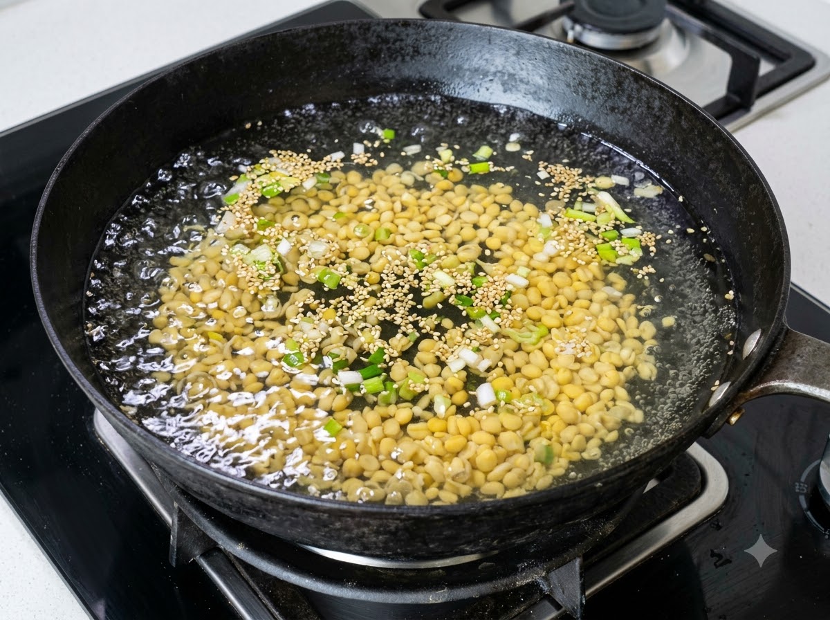 Une grande quantité de pousses de soja jaunes bouillant dans un wok deau avec des échalotes hachées.