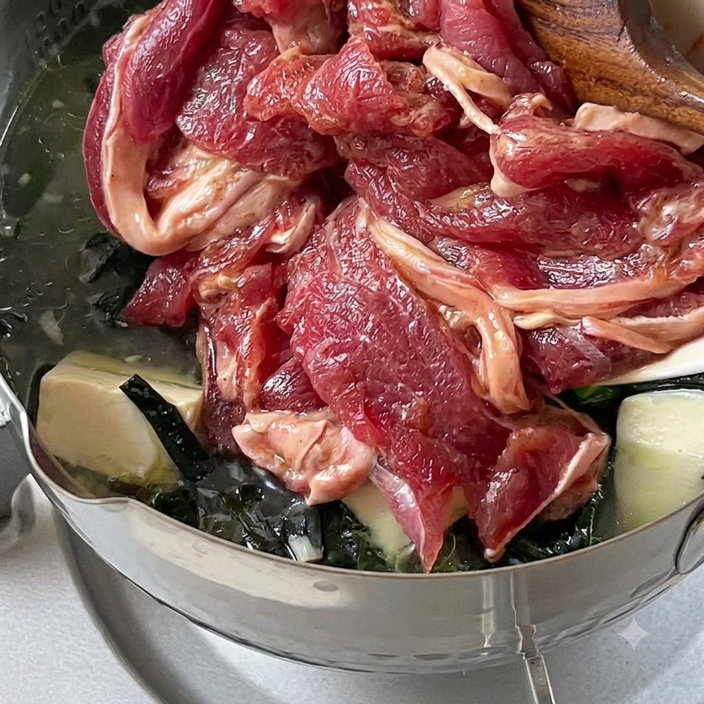 Tranches de bœuf mariné déposées dans une casserole de soupe mijotant à feu doux.