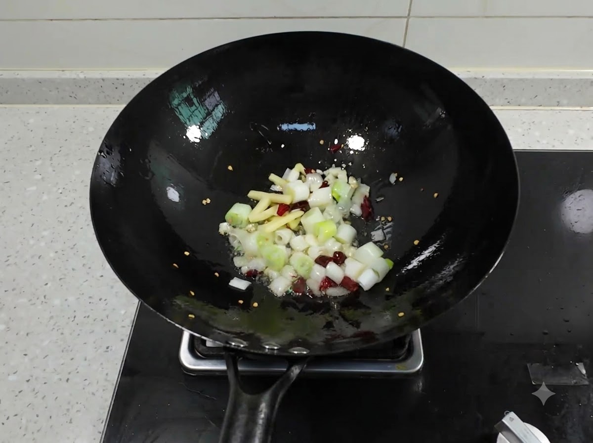 Ciboules hachées, gingembre, ail et piments séchés crépitant dans un wok noir avec de lhuile chaude.