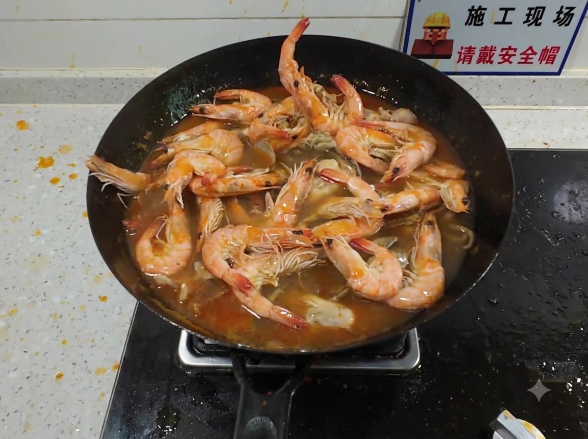 Un gros homard ajouté dans un wok rempli de fruits de mer mijotant et dun riche bouillon rouge.
