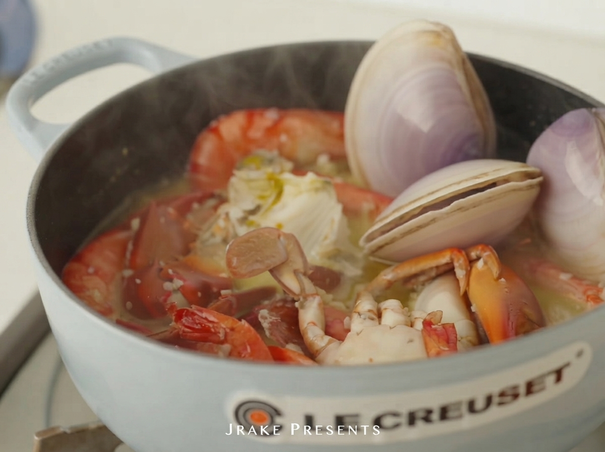 Palourdes crues et ormeau placés dans la cocotte avec les crevettes et le crabe.