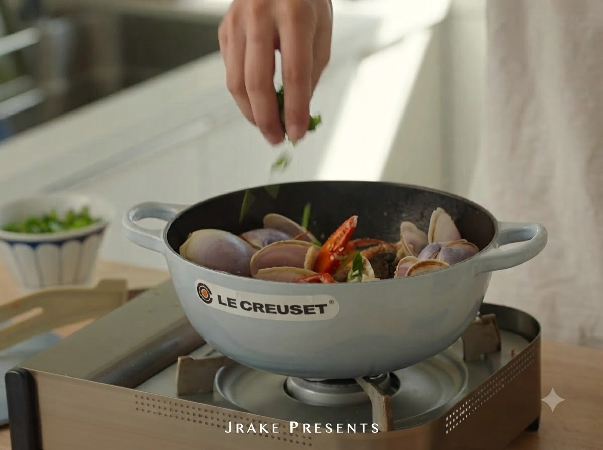 Coriandre hachée en train dêtre saupoudrée dans la cocotte sur les fruits de mer cuits.