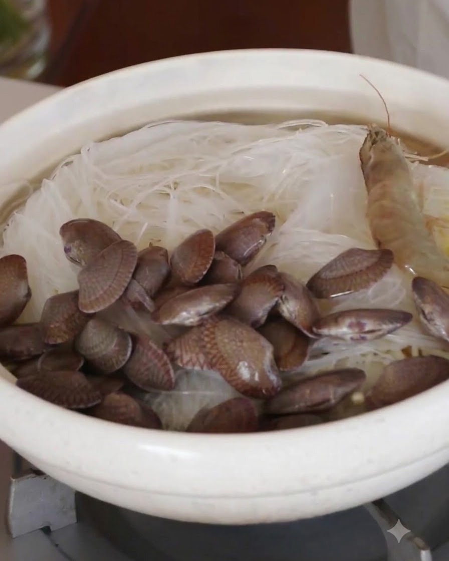 Des crevettes entières crues et des palourdes fraîches disposées en cercle sur les vermicelles.