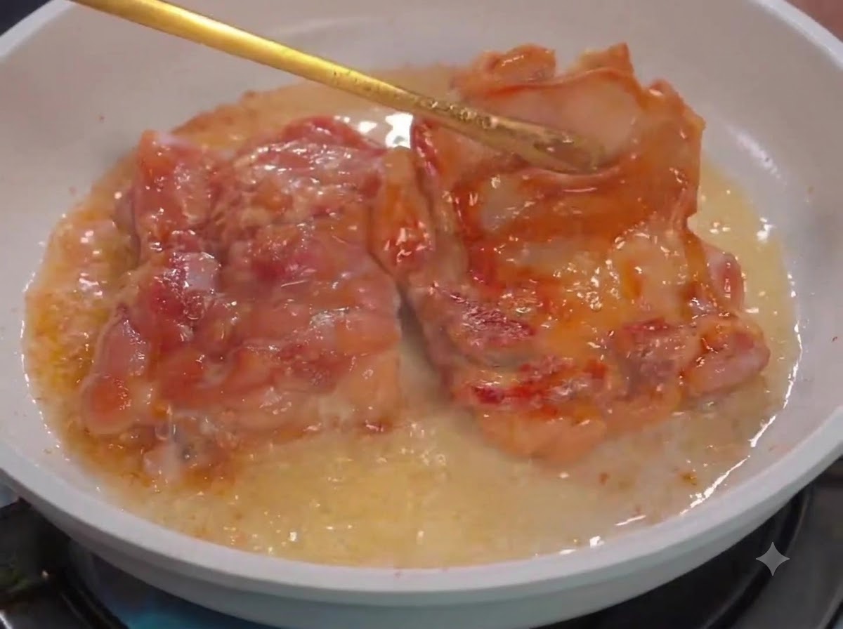 Pinces de cuisine retournant des morceaux de poulet dans une poêle blanche avec de lhuile.