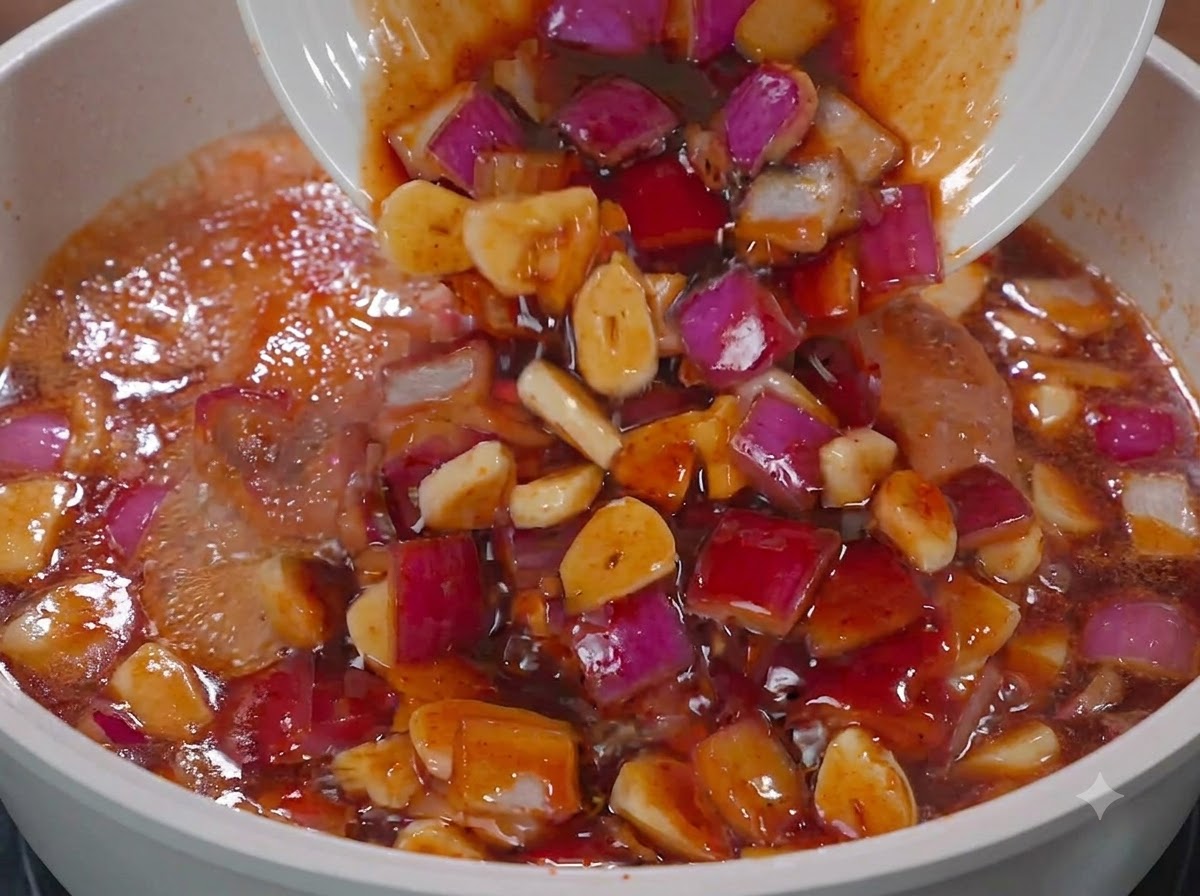 Sauce et oignons rouges versés dune assiette blanche dans une poêle avec du poulet.