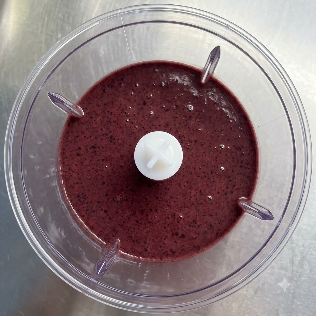 Un verre transparent en train dêtre rempli dun smoothie mixé dun violet riche.