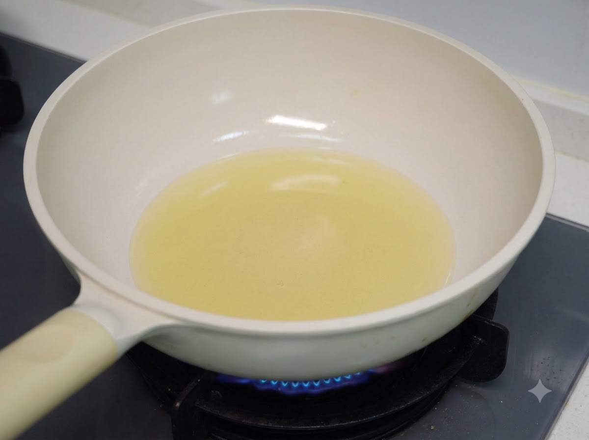 De lhuile de cuisson chauffant dans une poêle blanche sur un brûleur de cuisinière à gaz.