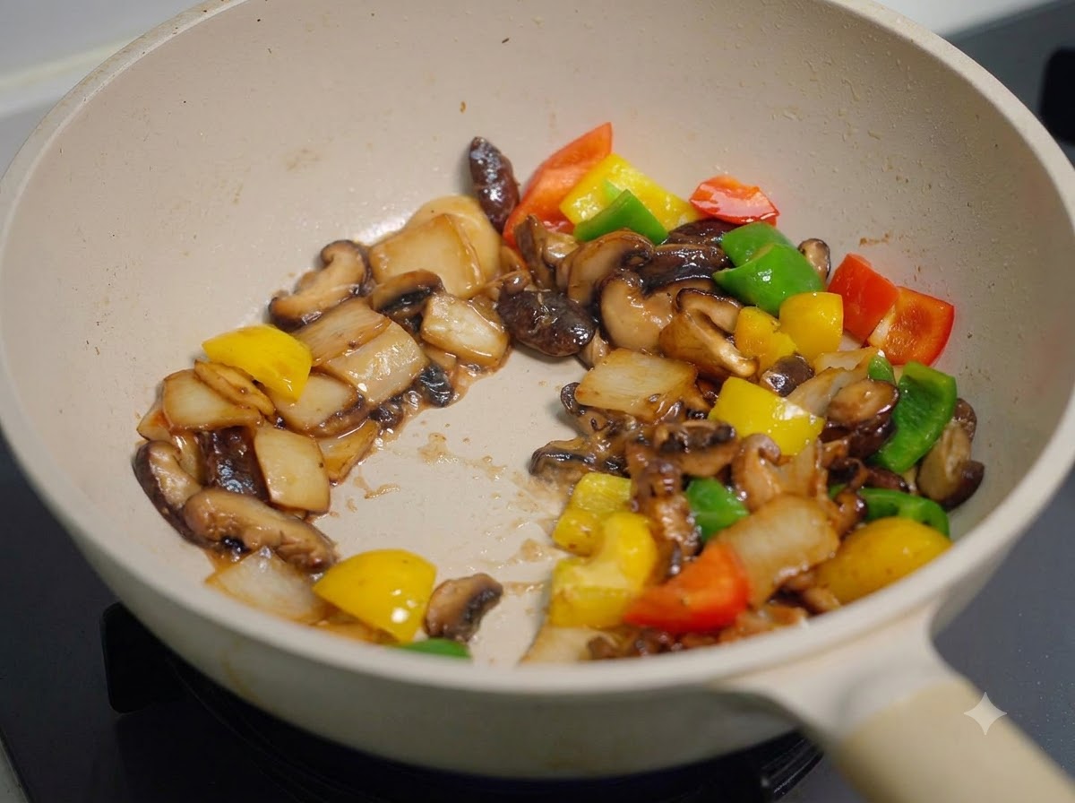 Tous les champignons et poivrons sautés et remués rapidement dans la poêle, uniformément enrobés dune sauce sombre et épaisse.