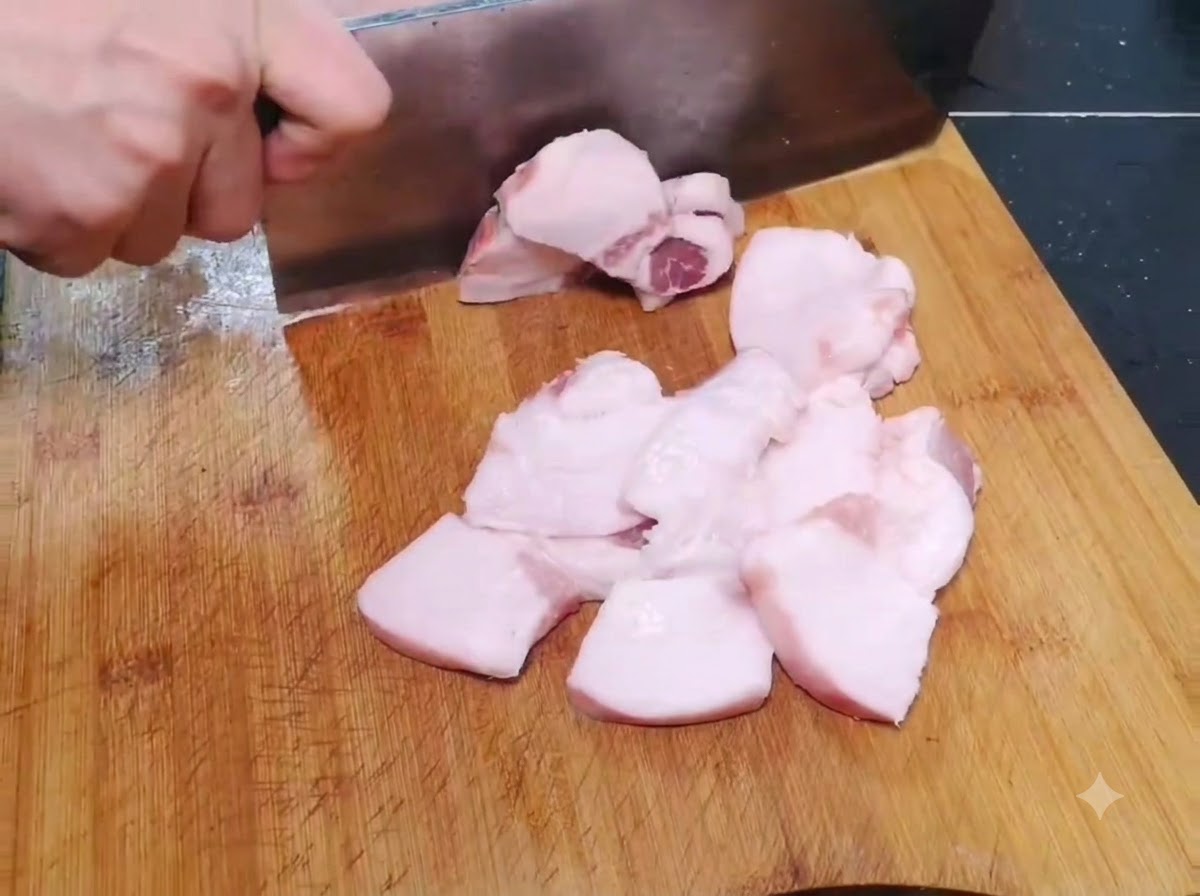 Des morceaux de porc cru fins et larges en train dêtre tranchés sur une planche à découper en bois.
