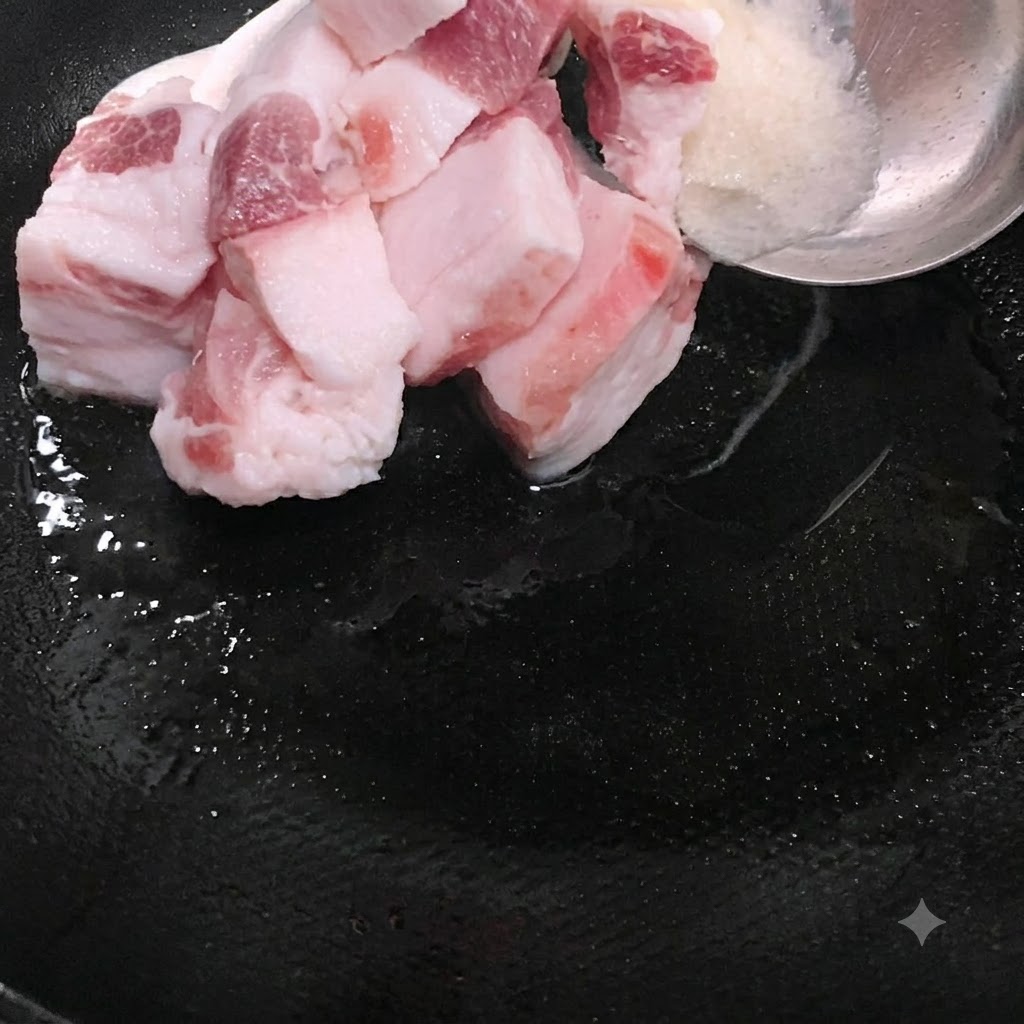 Des tranches de porc gras placées dans le wok aux côtés du saindoux fondu.