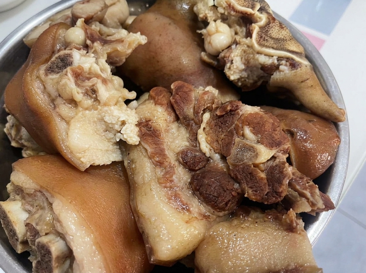 Morceaux de porc cuit reposant dans un bol, prêts à être coupés en morceaux plus petits.