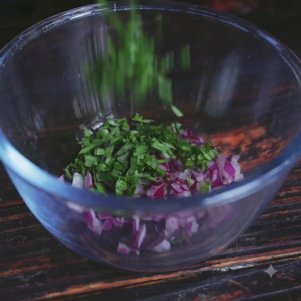 Herbes vertes fraîches ajoutées dans un bol en verre transparent contenant des oignons rouges hachés.