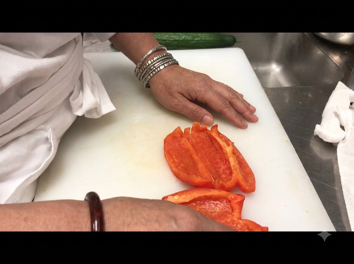 Des lanières de poivron rouge tranchées disposées sur une planche à découper blanche.