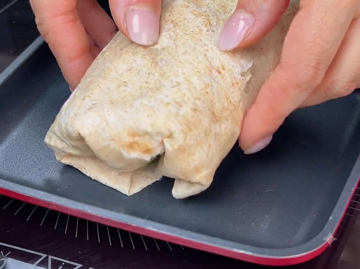 Un wrap roulé en train dêtre toasté dans une poêle chaude pour obtenir une croûte dorée.