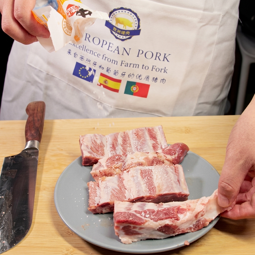 Du sel secoué dun emballage sur des travers de porc crus reposant sur une assiette à côté dun couteau de chef.