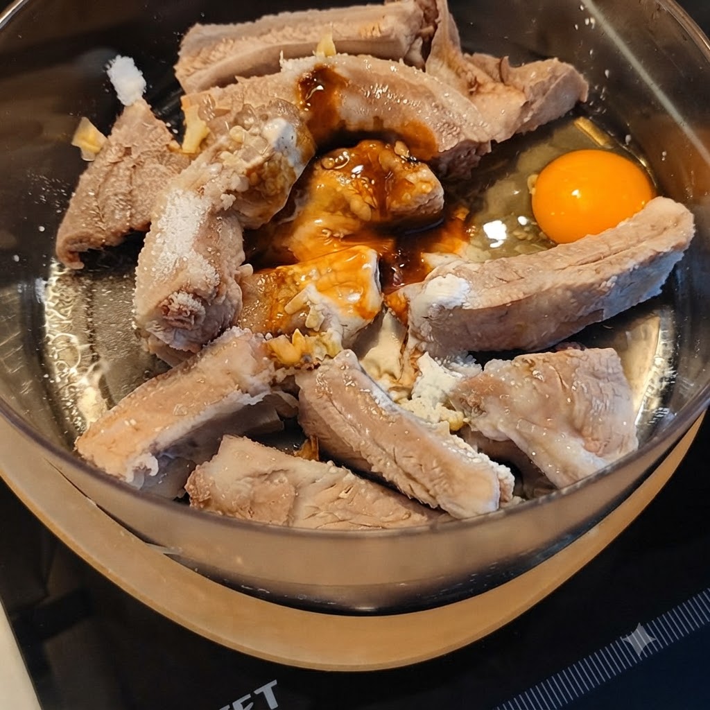 Travers de porc en cours de marinade avec diverses sauces et un œuf cassé dans un bol mélangeur.