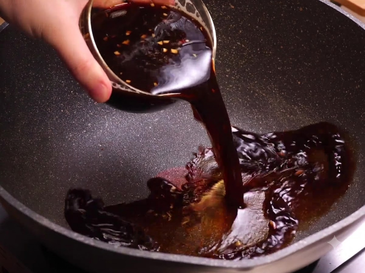 Un bol de sauce au café foncée versée dans un wok chauffé.